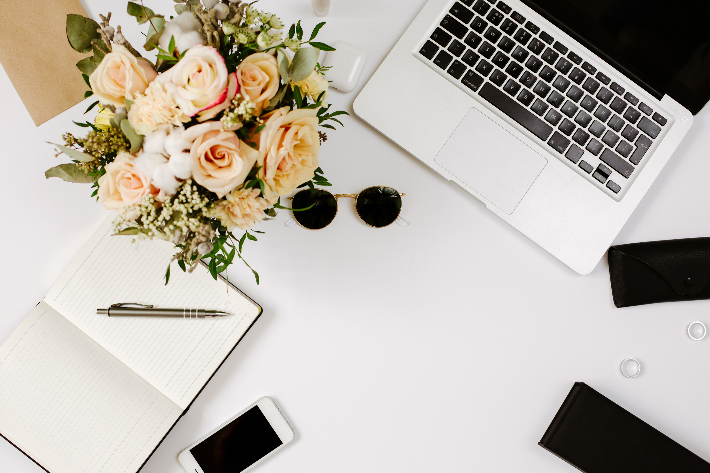 Office desk workspace with computer, flowers bouquet and stationery on white table. Flat lay, top view